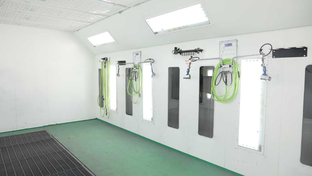 A spraymask room with walls outfitted with spray guns, hoses, and other neatly organized tools, ready for use.